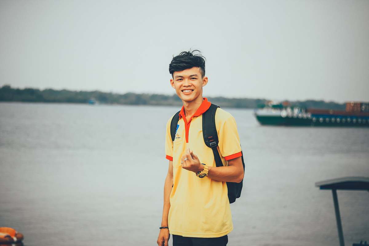 people person standing near body of water while doing finger heart hand gesture at daytime person