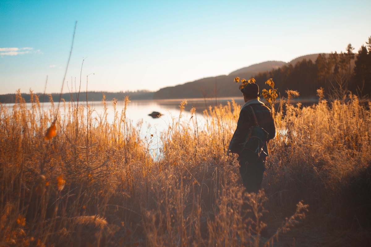 people person standing on grass field near lake and mountain range person