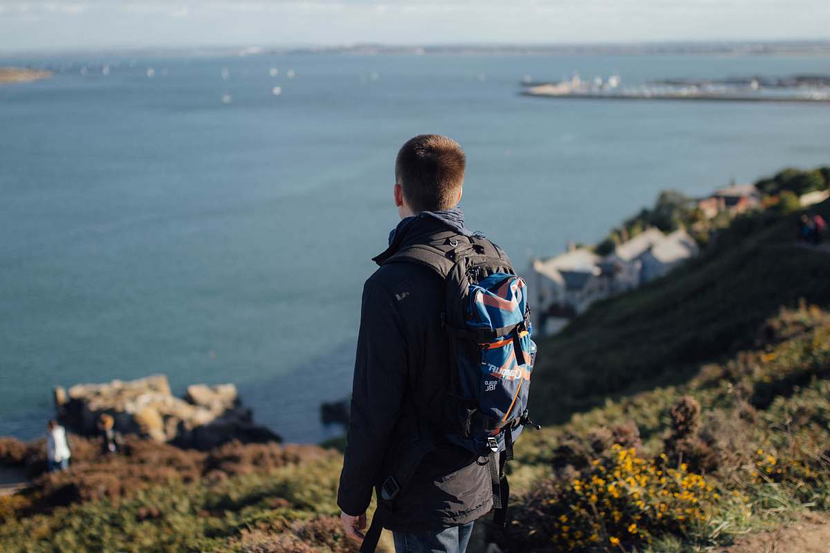 people person standing on mountain cliff facing sea person