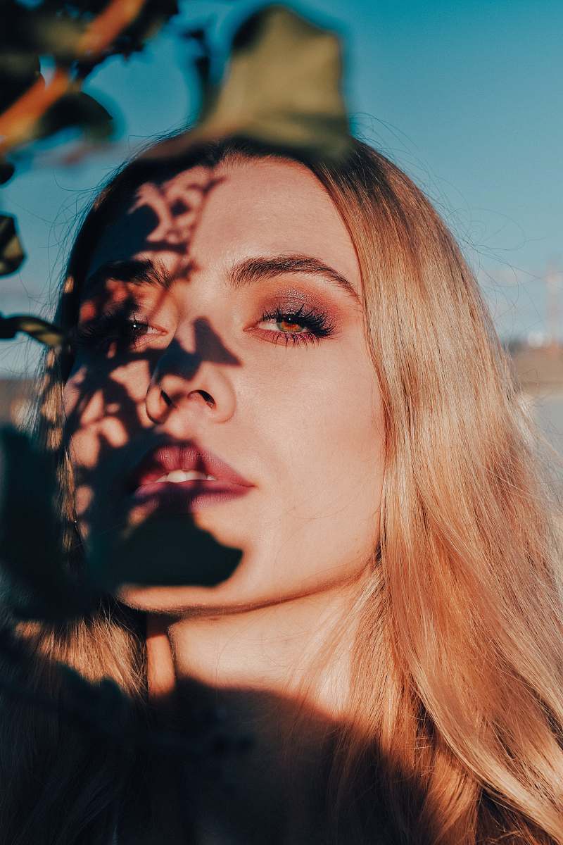 people plant leaves shadow casted on woman's face during daytime person