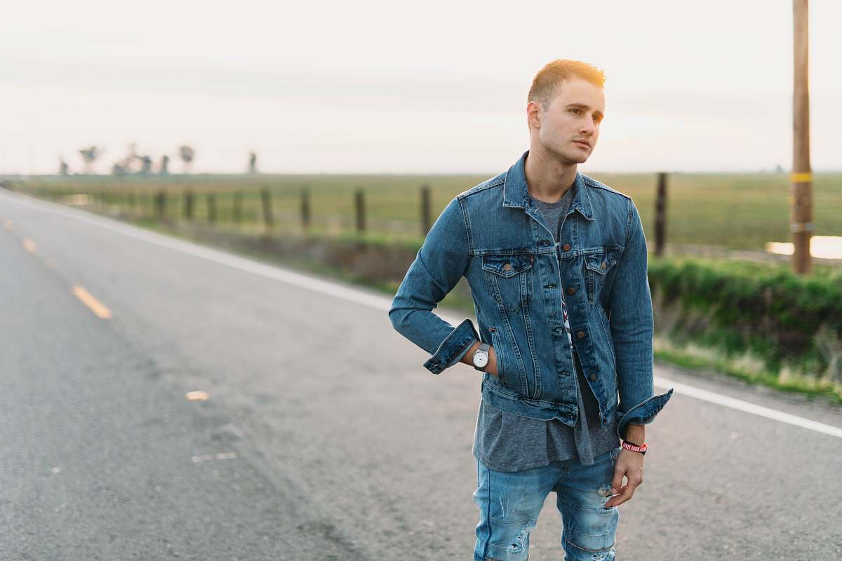 person rule of thirds photography of man standing in the middle of road denim