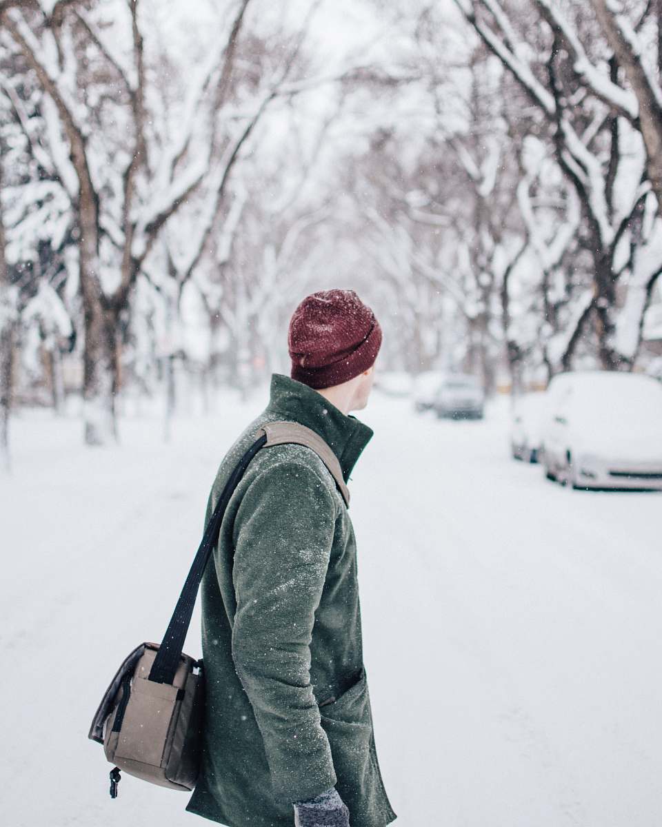 people selective focus photography of man wearing coat and beanie standing watching vehicle on road person