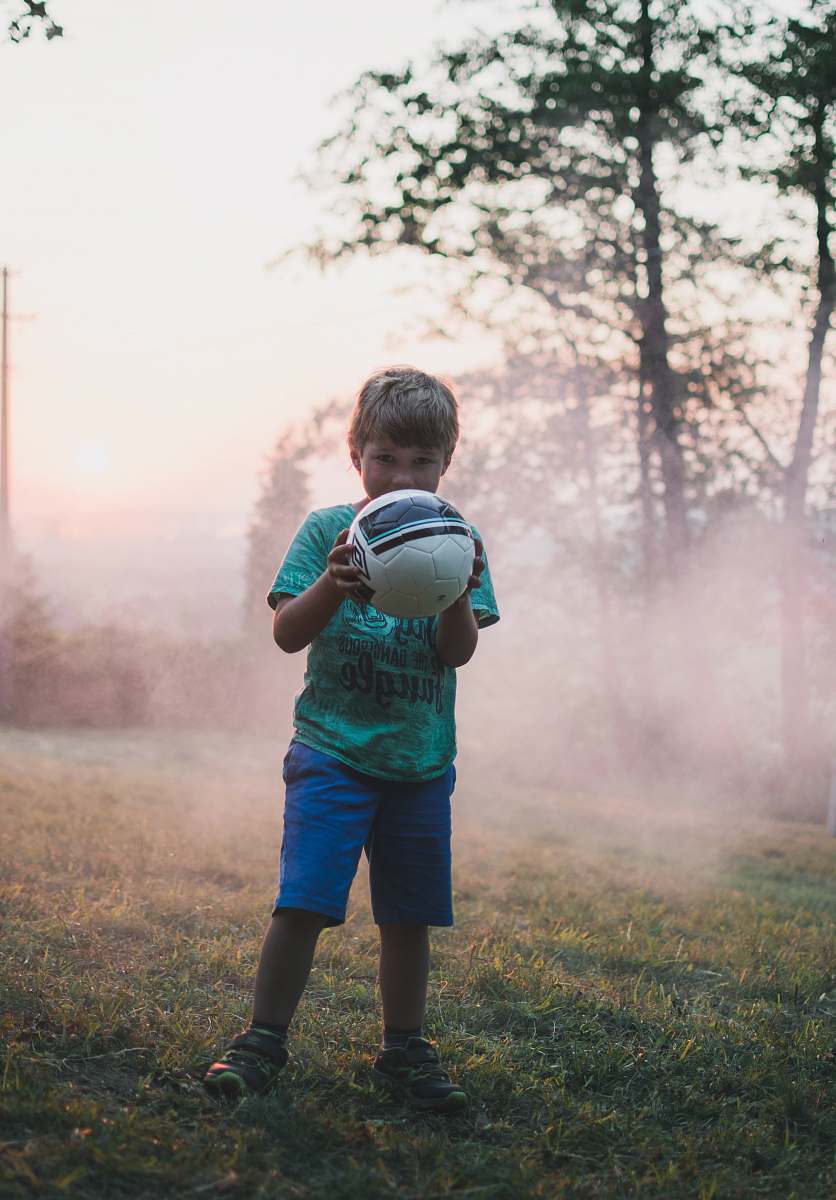 people shallow focus photography of boy holding a ball person