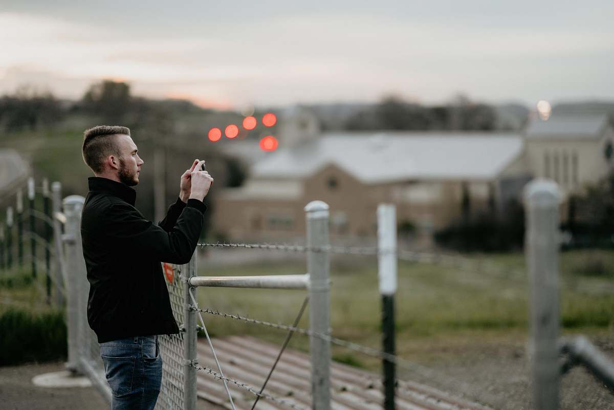 person shallow focus photography of man taking a photo near fences people