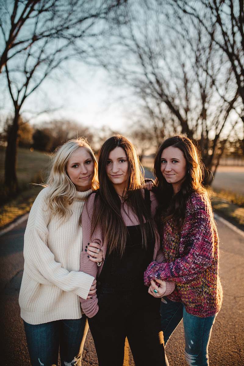 people shallow focus photography of three women standing along trees person