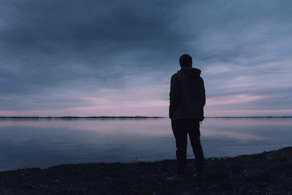 people silhouette of man standing near body of water person