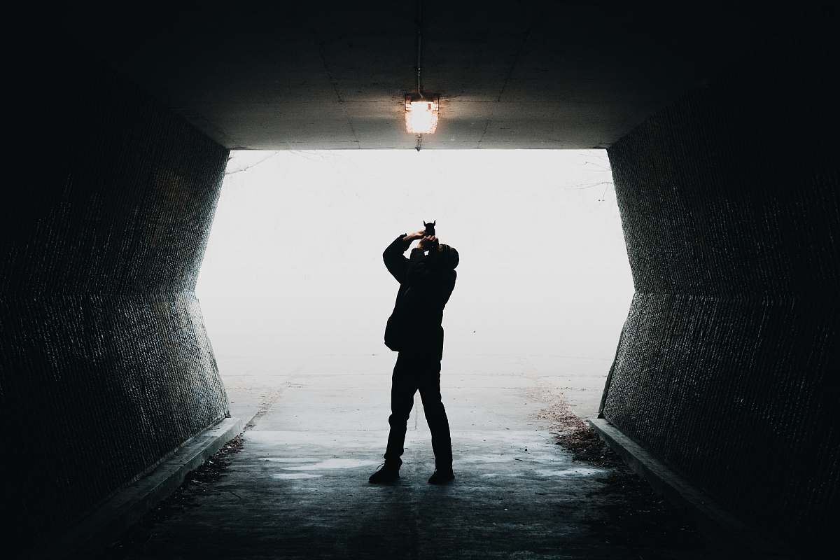 people silhouette of man taking photo of light inside tunnel way person