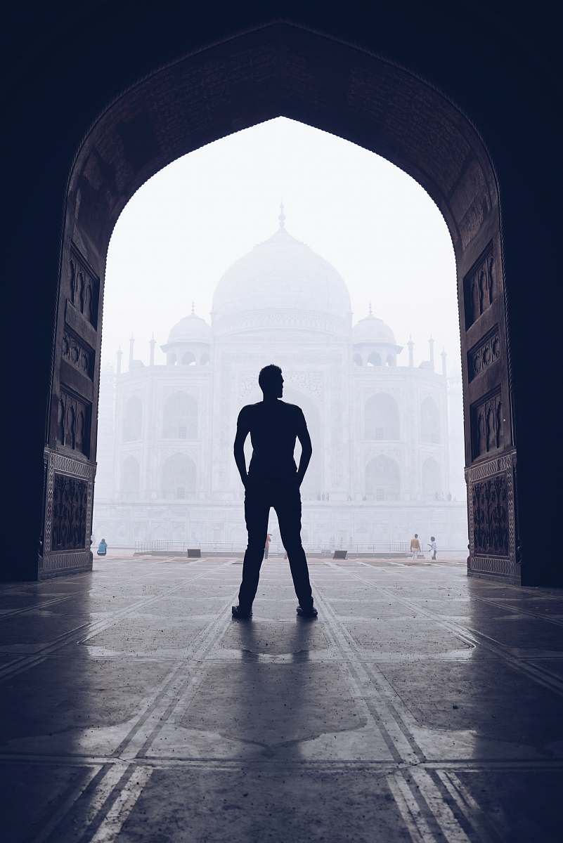 person silhouette photography of man standing near door in front of mosque people