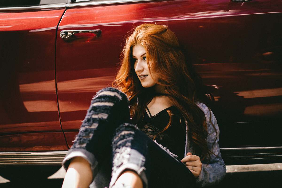 people smiling woman sitting beside red car woman