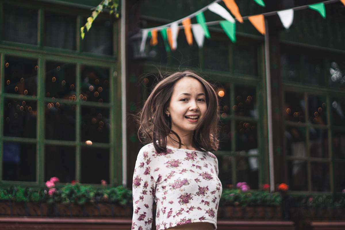 people smiling woman standing under multicolored buntings during daytime person