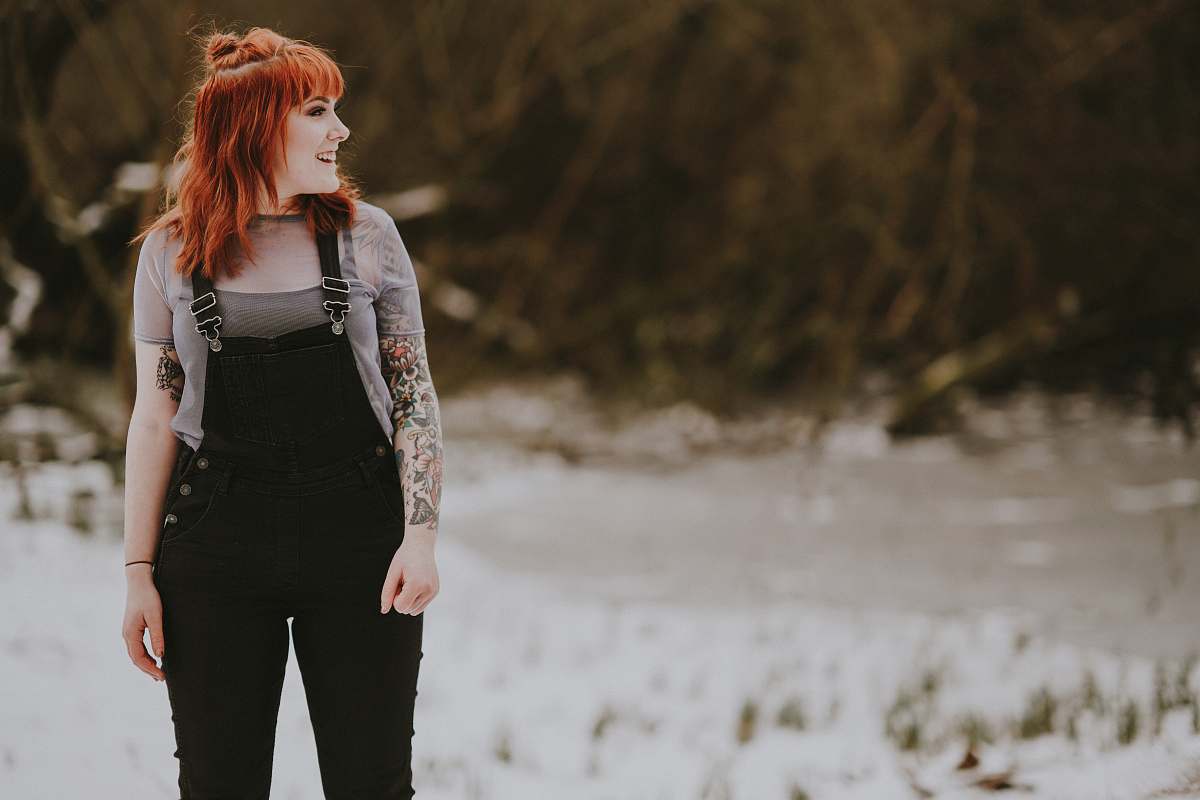 people smiling woman wearing black overalls standing on white ground at daytime person