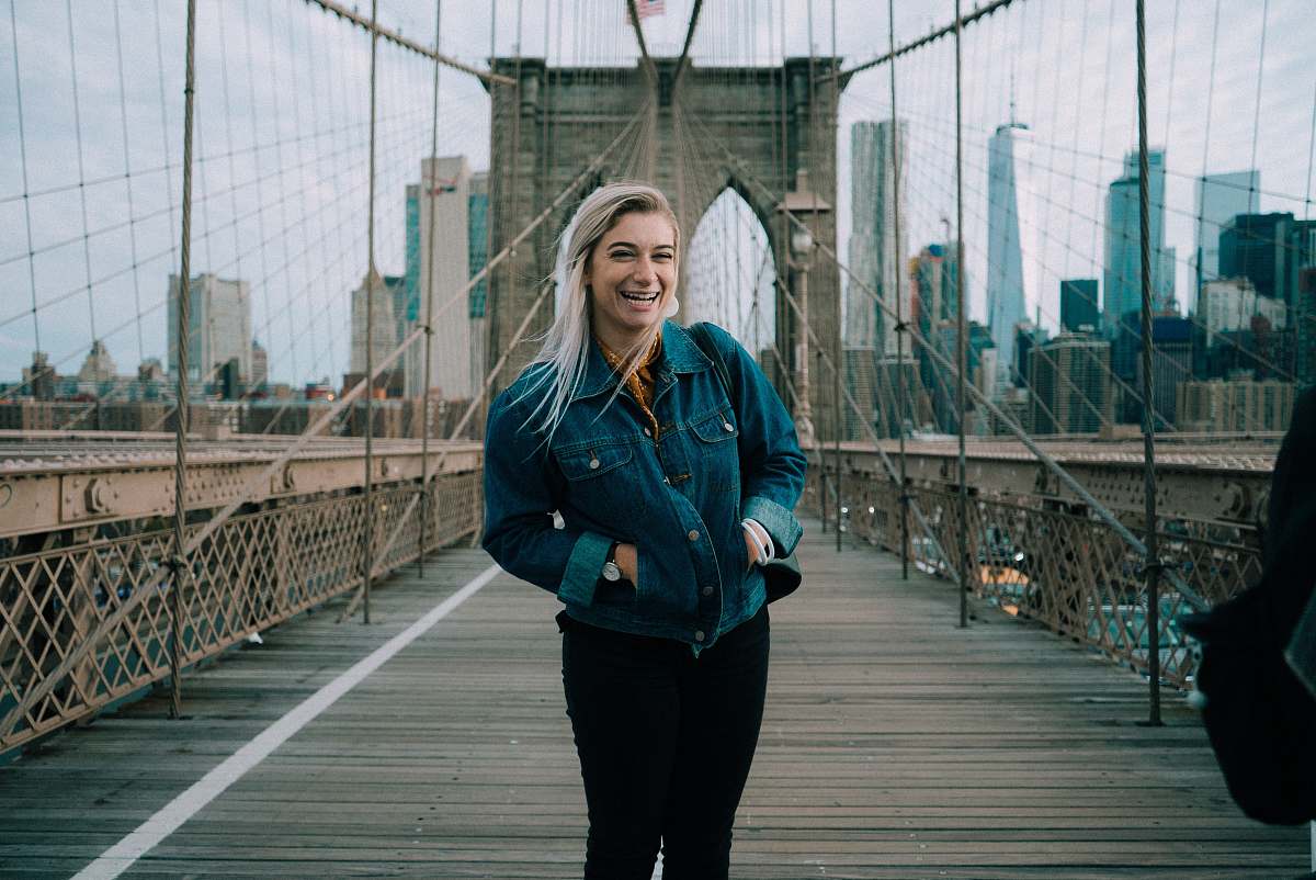 people standing smiling woman wearing blue denim button-up jacket at Brooklyn Bridge person