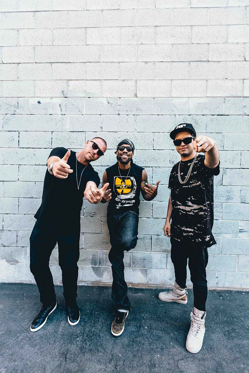 people three man standing behind gray concrete wall at daytime person