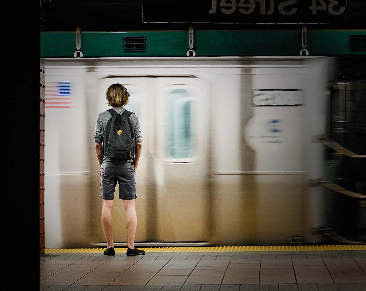 people time lapse photography of man standing in front of train person