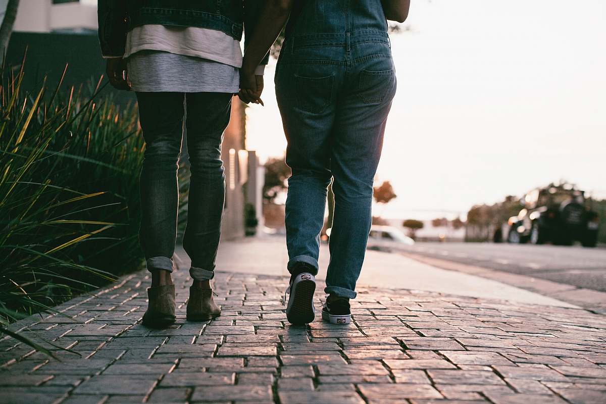 people two people walking on the pavement during daytime person