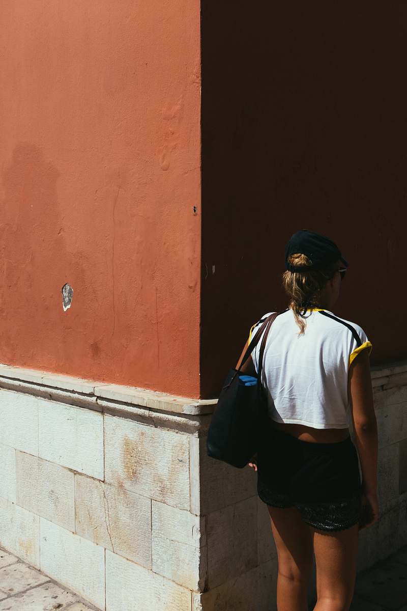 This striking image captures a woman strolling confidently down a charming cobblestone street in a historic old town. The scene emanates a sense of exploration and urban adventure, perfect for travel blogs, tourism websites, or any project highlighting city life and cultural experiences. The juxtaposition of the woman's figure against the picturesque architecture invites viewers to imagine their own journey through these timeless streets.