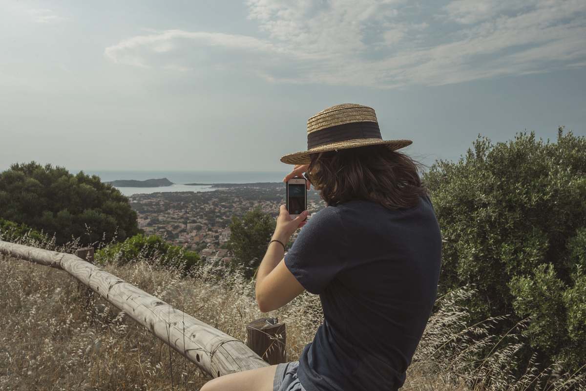 people woman holding smartphone taking pictures of trees and mountain under clear blue sky person
