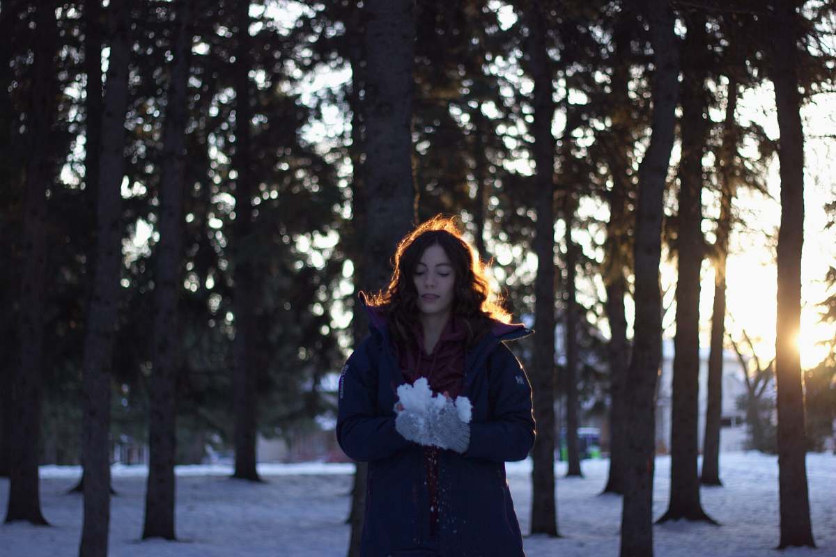 people woman holding snow near trees during sunset person
