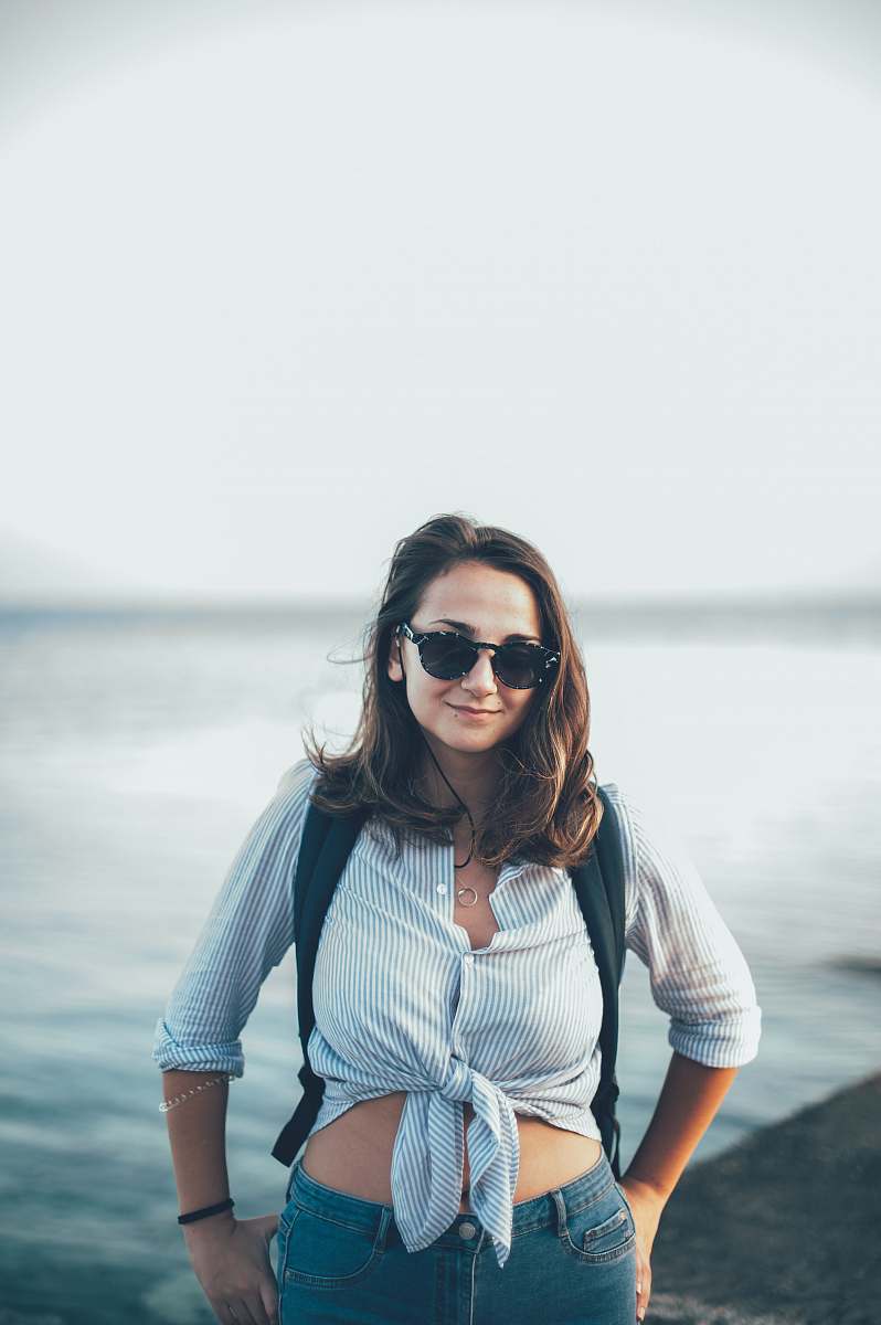 people woman in blue crop-top standing beside body of water person
