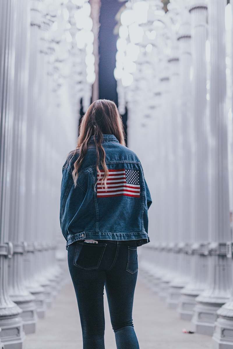 people woman in blue denim jacket standing near pedestals person