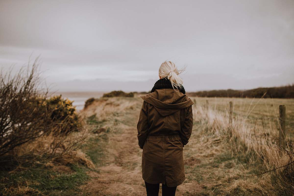 people woman in brown coat walking on brown grass person