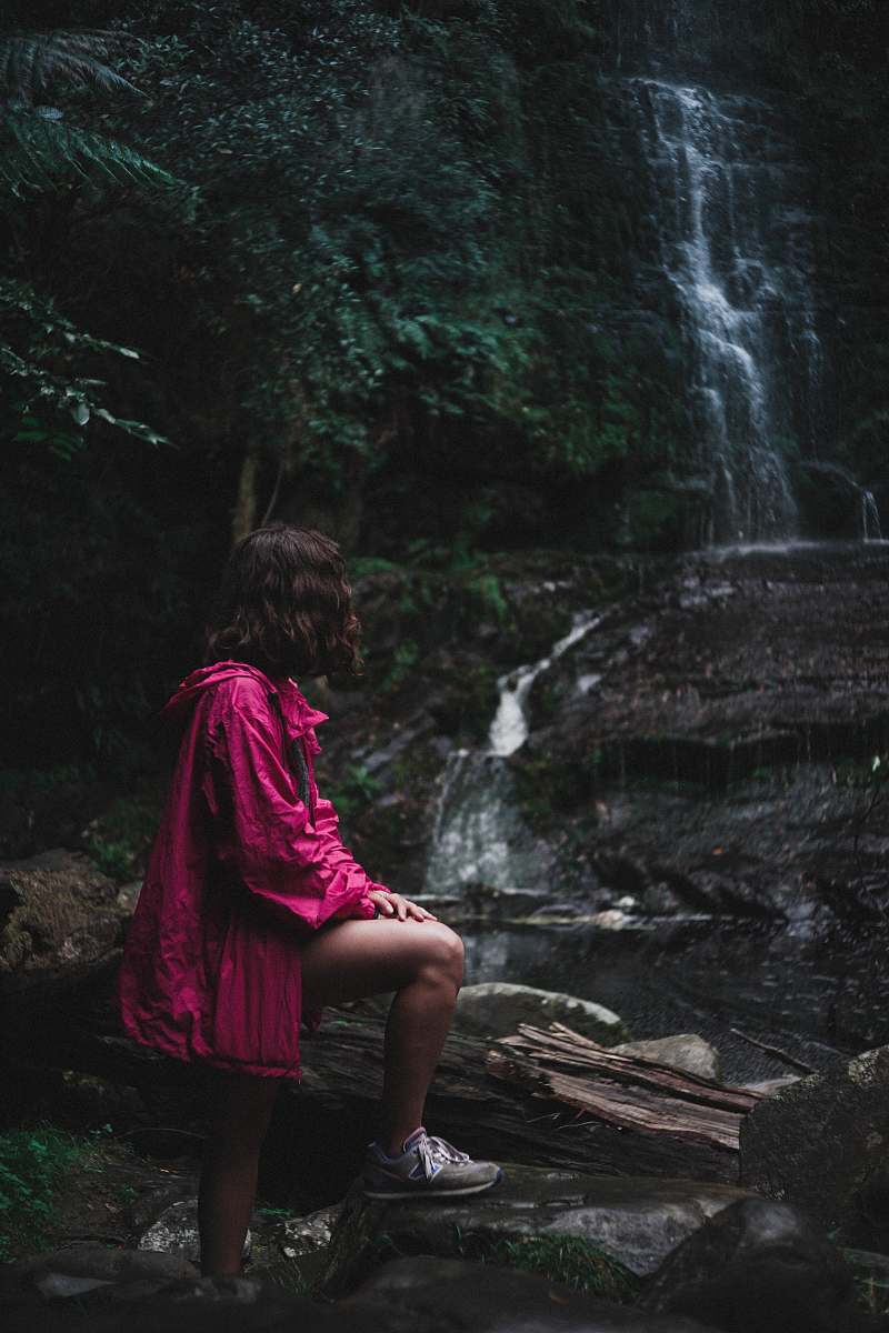 people woman in purple jacket standing near waterfalls person
