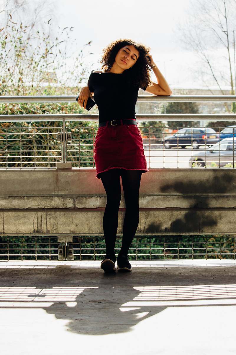 people woman in red skirt leaning on gray steel tube person