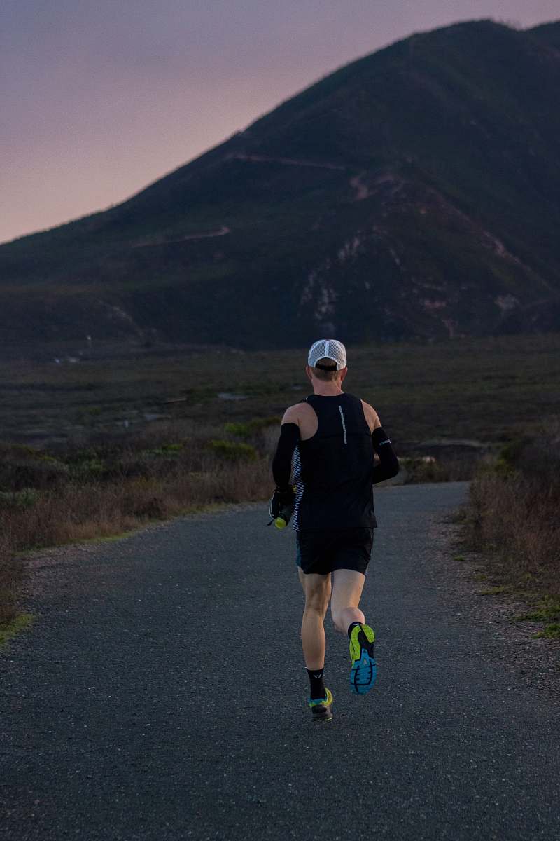 people woman jogging on gray road across mountain during daytime person