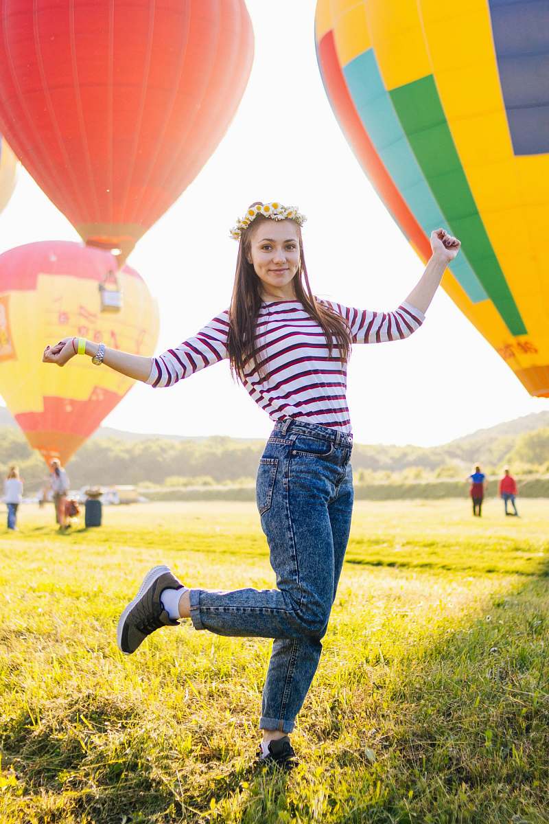 people woman posing on grass field surrounded with hot air balloons balloon