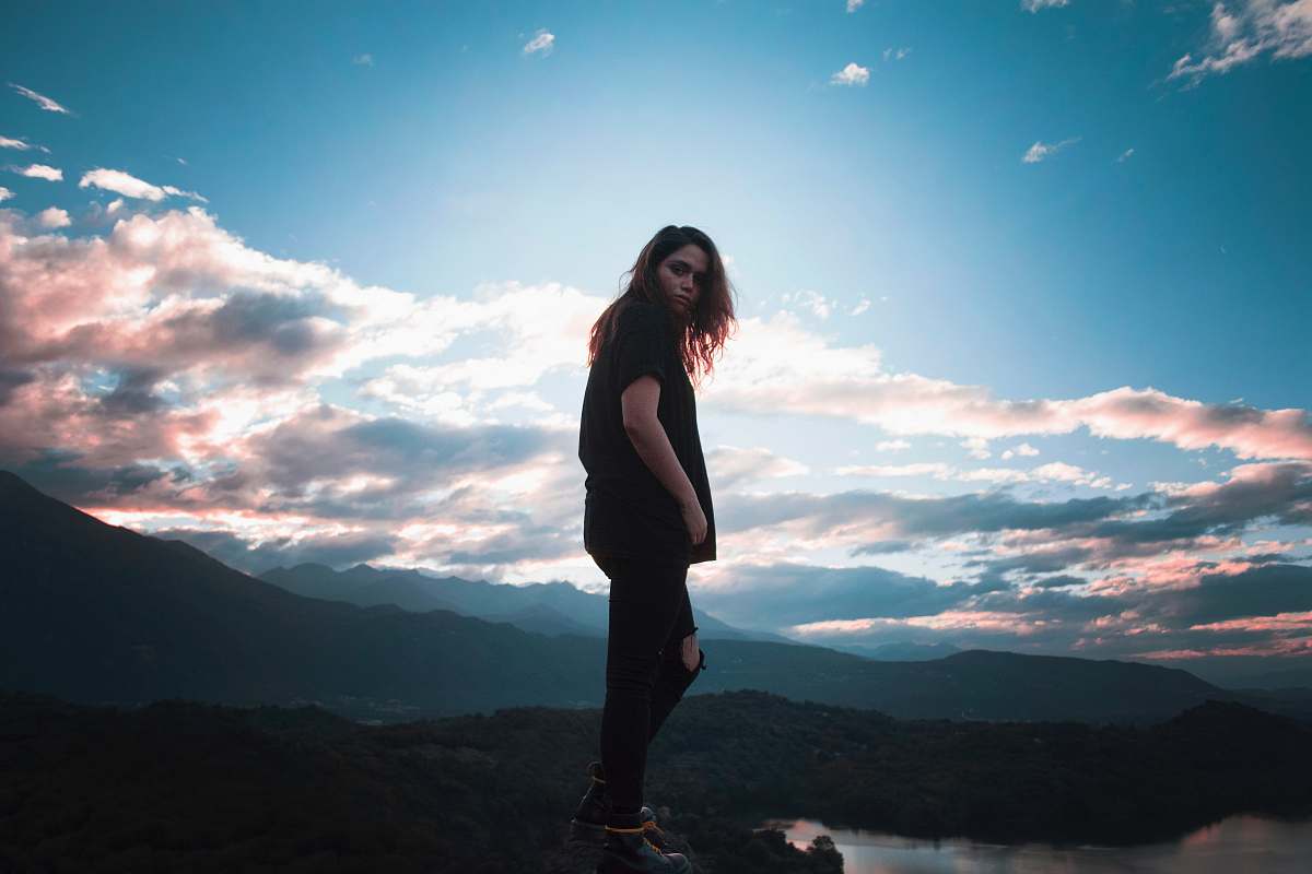 person woman putting her hand in pocket standing near mountain people