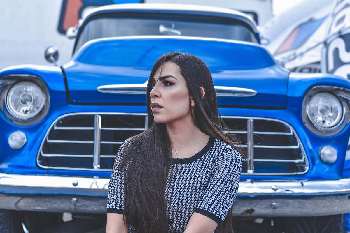people woman sitting beside blue car person
