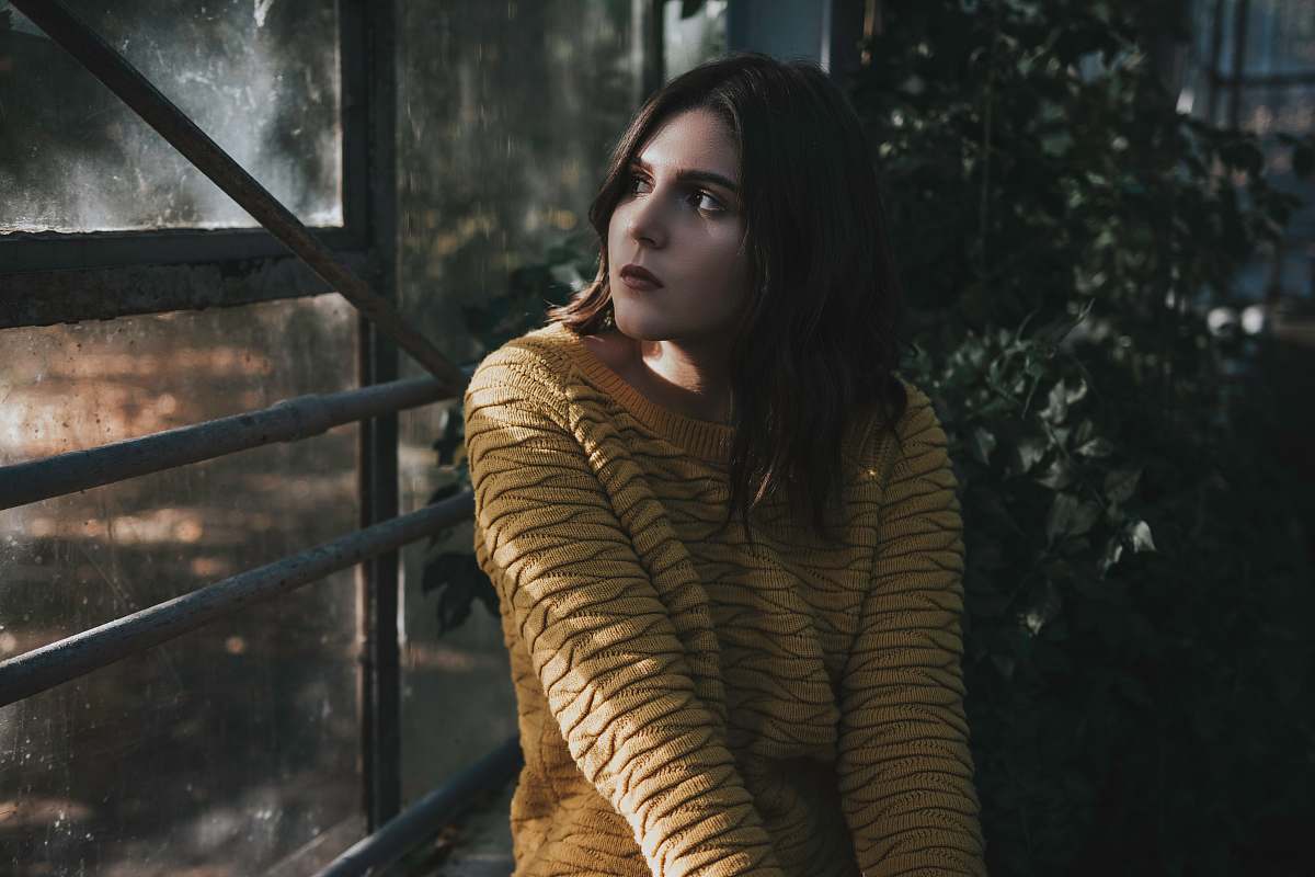 This captivating image captures a woman seated on a bench in a tranquil forest setting, with light streaming through the leaves and creating a serene atmosphere. The scene depicts a perfect moment of reflection and peace, ideal for projects focused on mindfulness, nature, and relaxation. Whether used in marketing materials, blogs, or artistic projects, this image evokes a sense of calm and introspection.