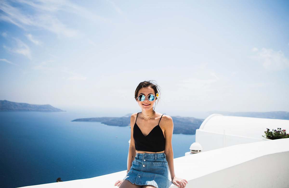 people woman sitting on white barrier near sea during daytime person