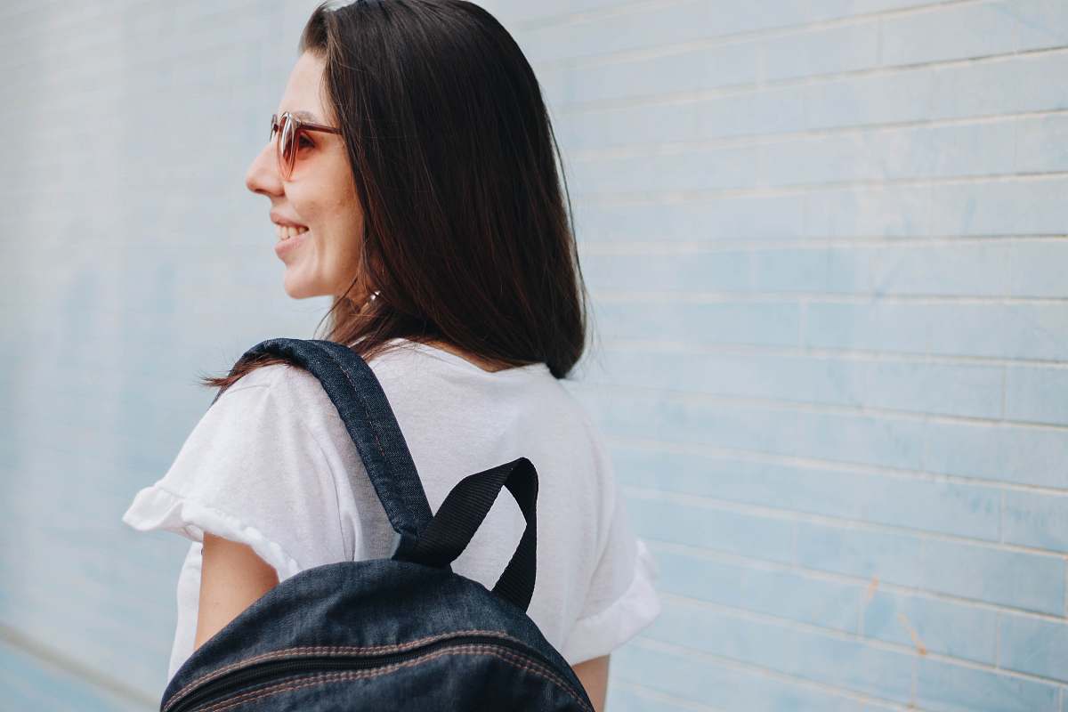 person woman smiling while carrying blue denim backpack people