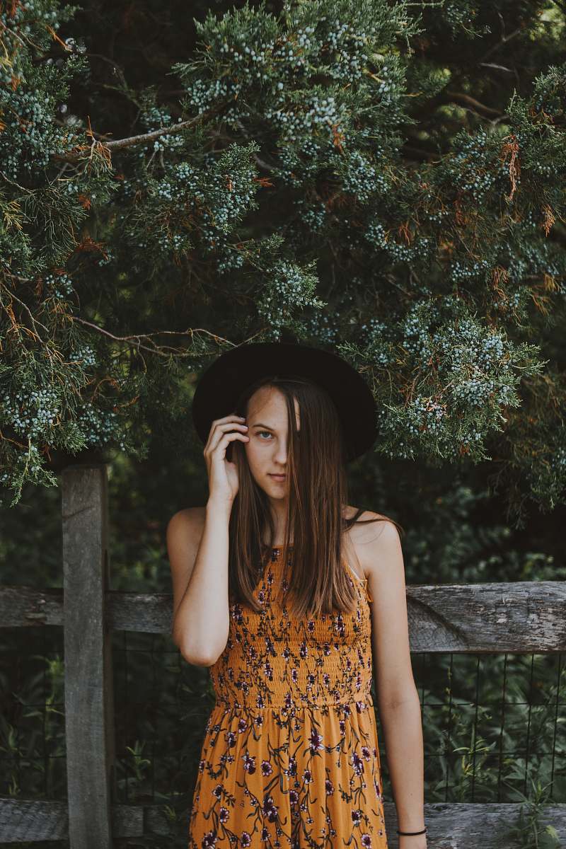 people woman standing in front of brown wooden fence during daytime person
