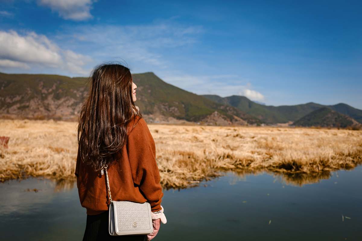 people woman standing in front of green mountain under blue sky person