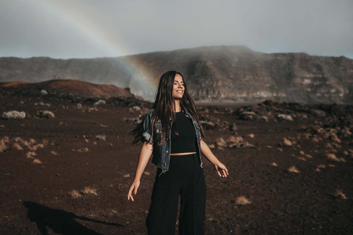 people woman standing on mountain behind rainbow person