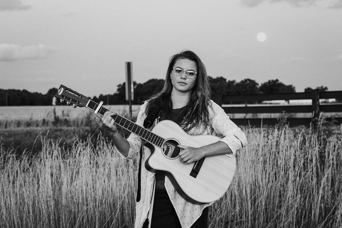 people woman standing while playing guitar black-and-white