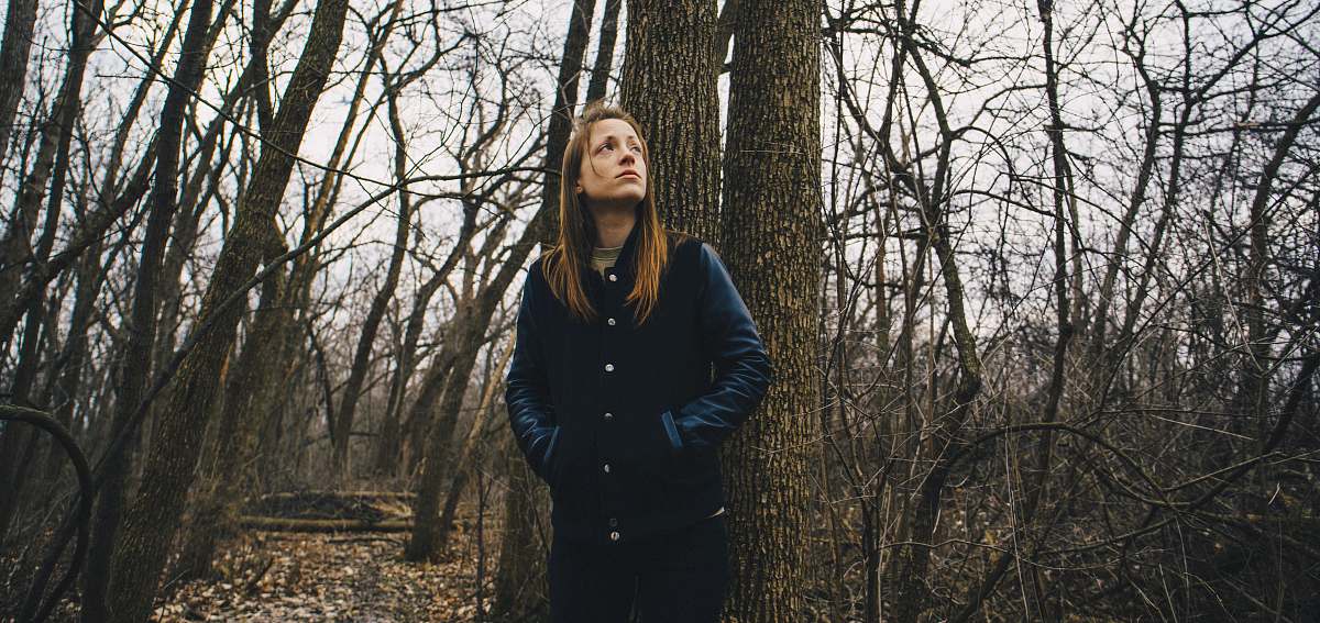 people woman staring up while leaning on brown tree forest