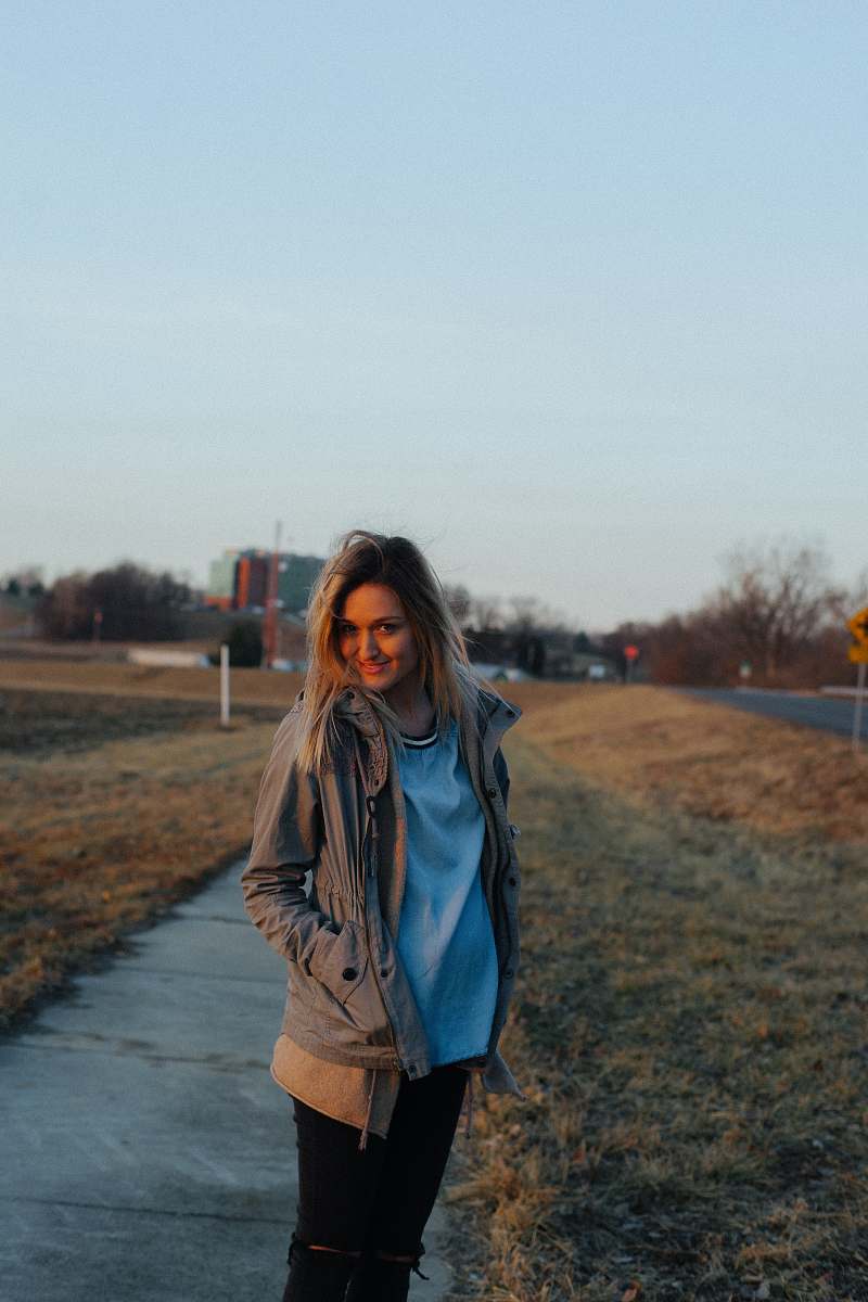 person woman walking on sidewalk near grass field during daytime people