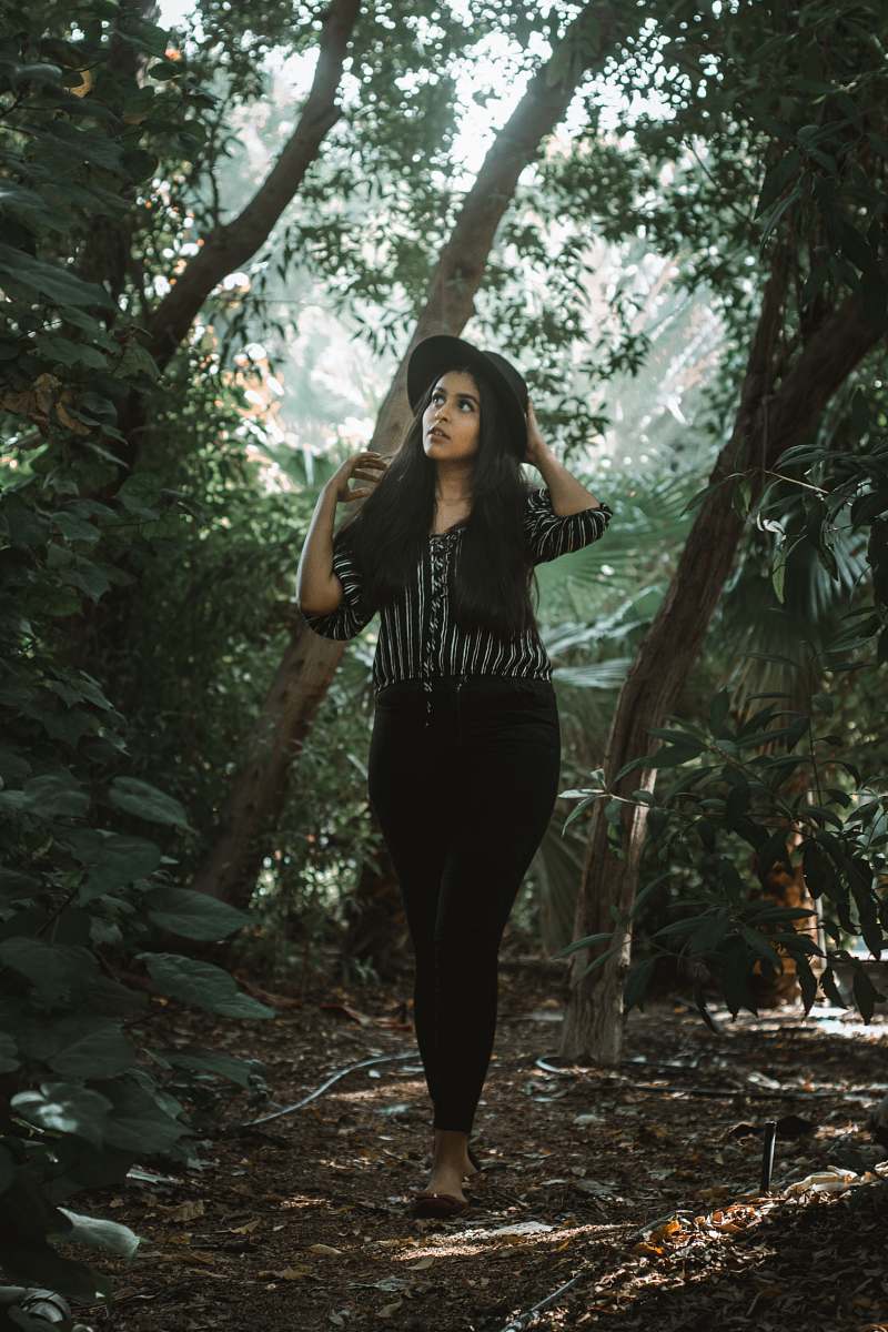 people woman walking while looking on her left side and holding her hat during daytime person