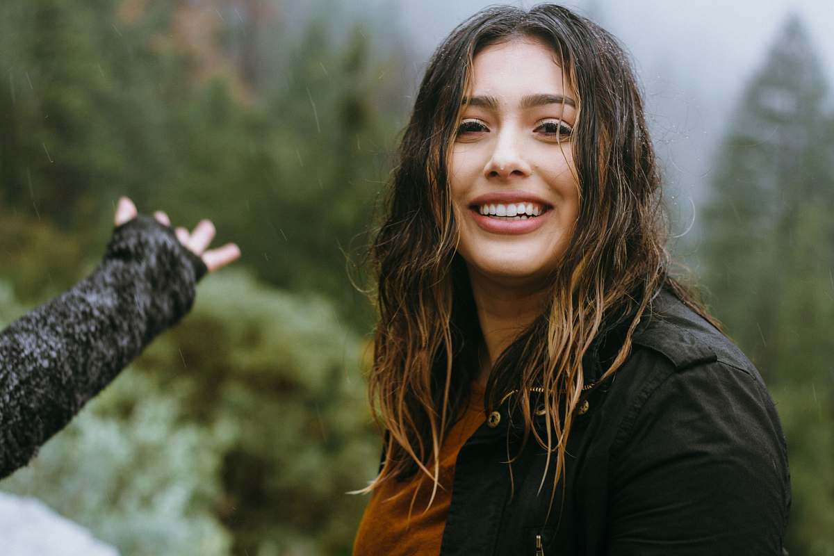 people woman wearing black jacket smiling with forest background person