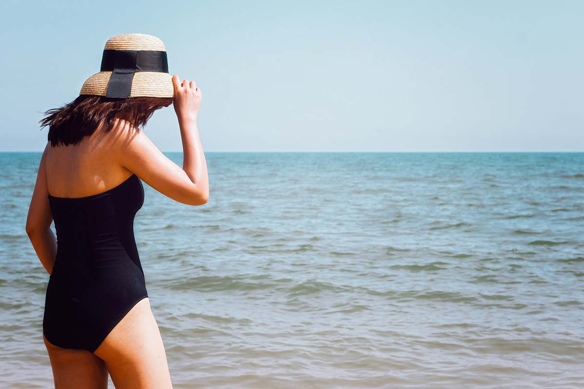 people woman wearing black onepiece swimsuit standing beside seashore at daytime person