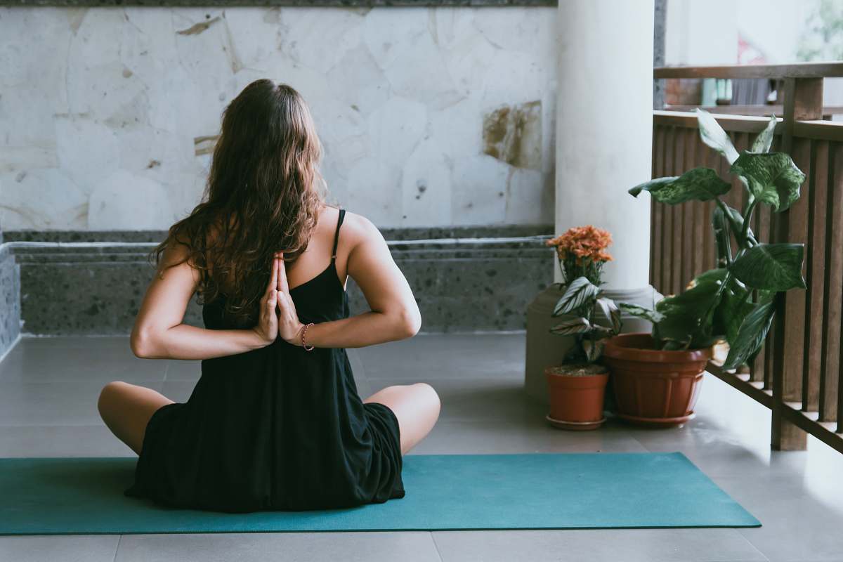 plant woman wearing black shirt sitting on green yoga mat yoga