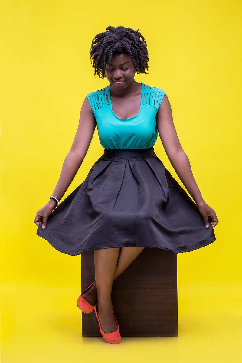 people woman wearing blue and black sleeveless dress sitting on brown wooden chair person