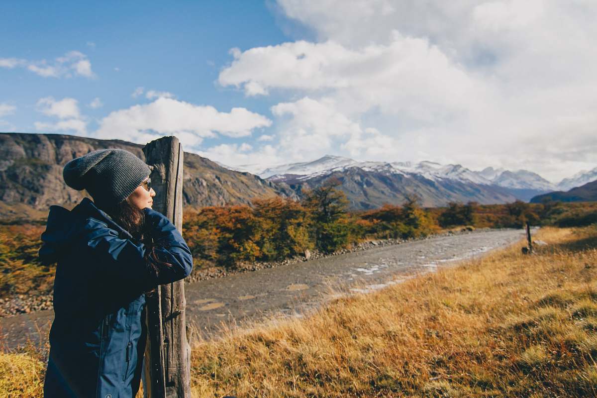 people woman wearing blue jacket leaning on brown wooden post person