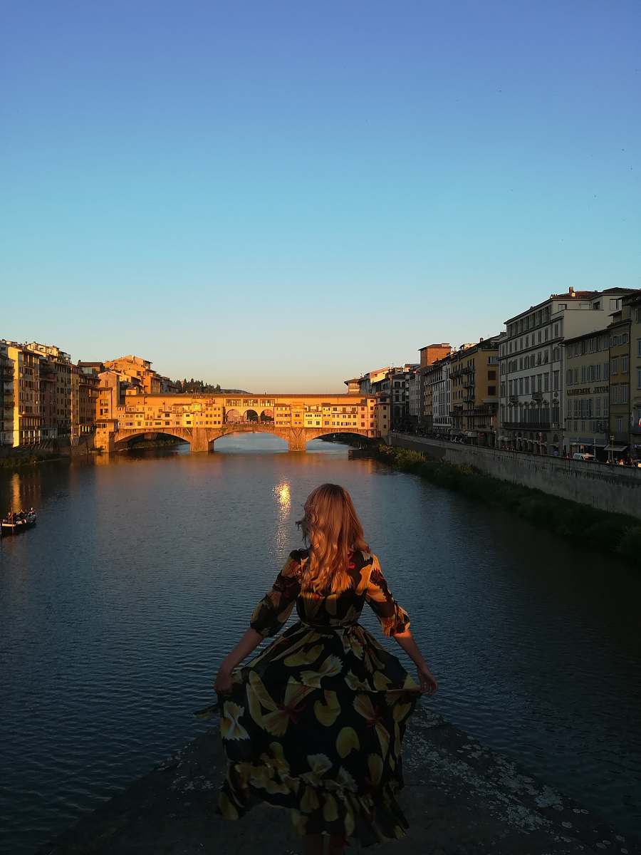 people woman wearing brown and black floral 3/4-sleeved dress standing beside river person