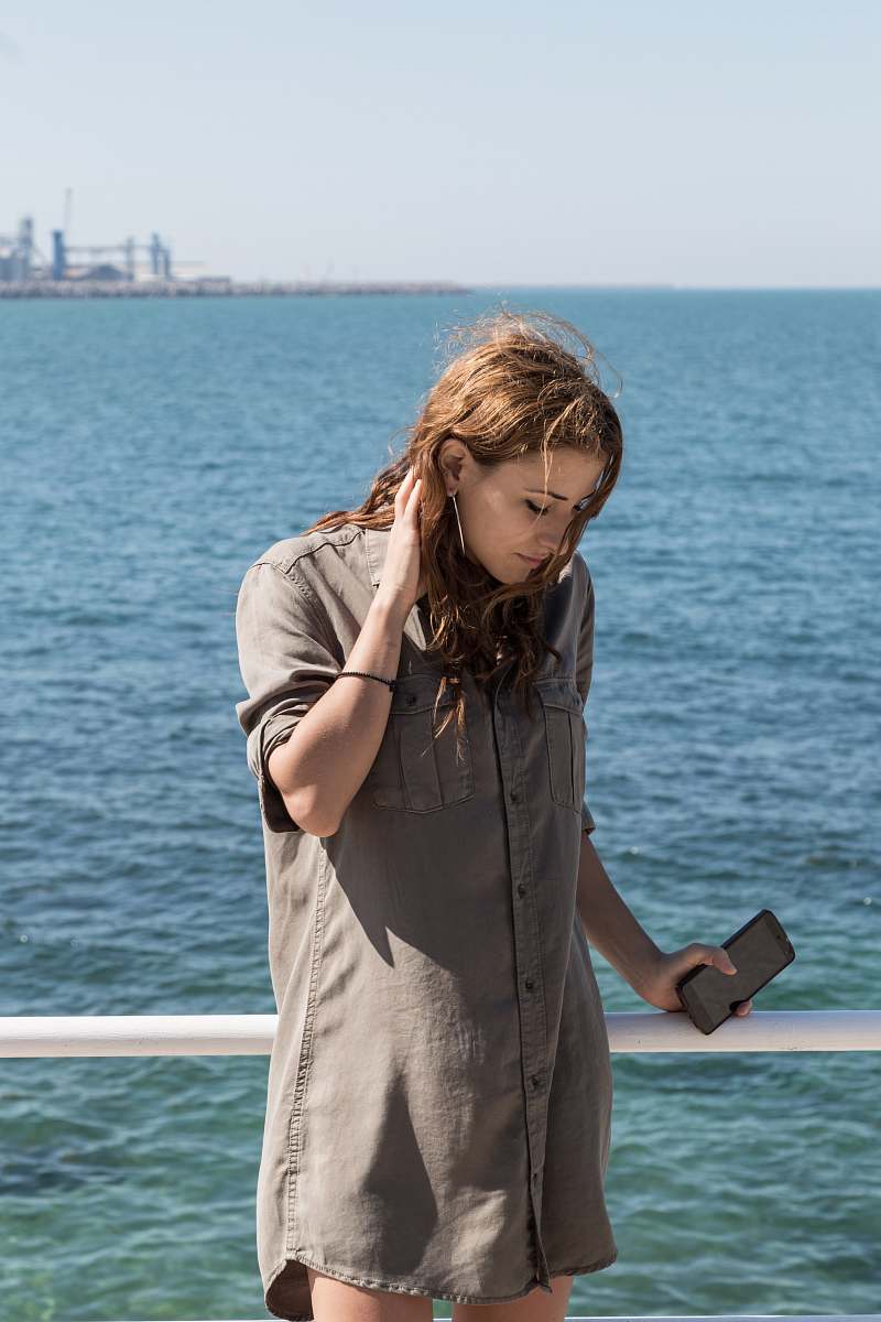 people woman wearing brown button-up long-sleeved dress beside large body of water during daytime person