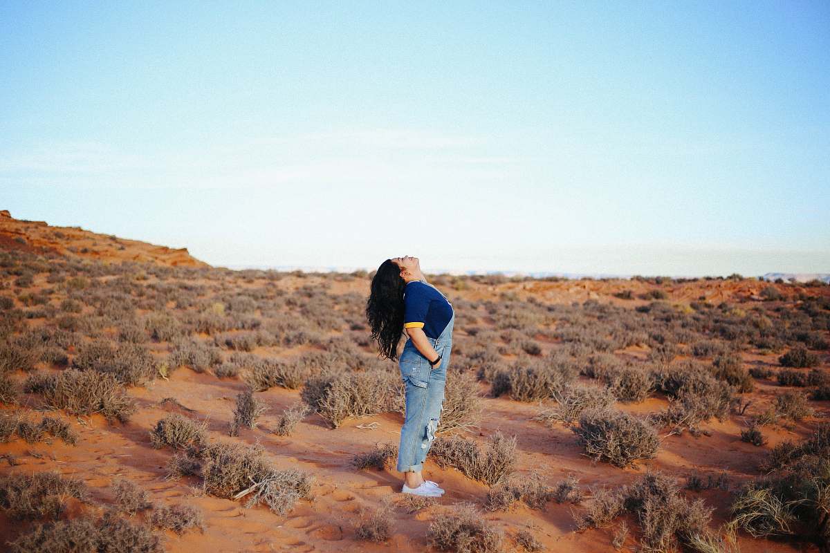 people woman wearing denim jumper suit looking up in middle of field person