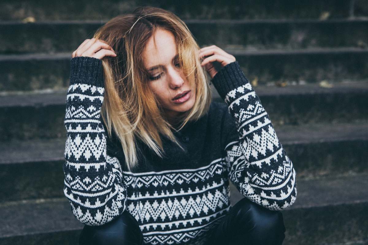 people woman wearing white and black sweater sitting on stair person